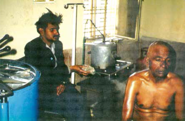 A therapist at an Ayurvedic Hospital in Jaipur, India, holds a nozzle attached to a tube from a boiling pot of herbs selected for their antiinflammatory effects, and sprays medicated steam on the shoulder of a patient suffering rheumatoid arthritis. (Photo taken by Bruce in 1990.)